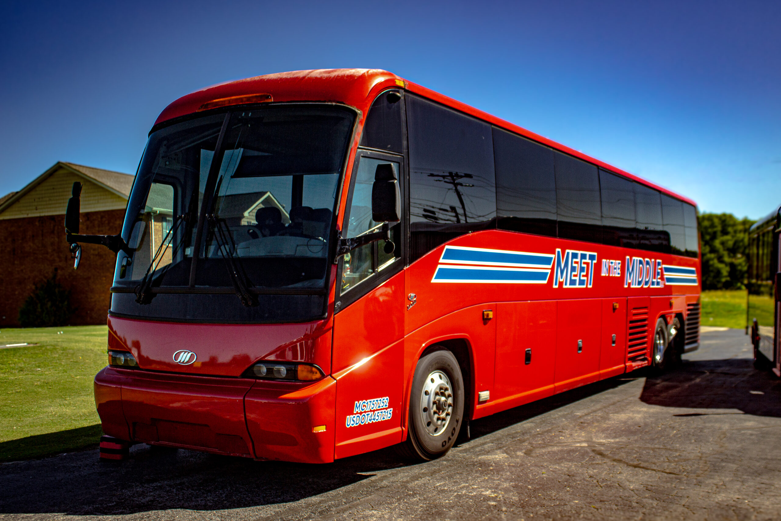 Red 56-passenger charter bus operated by Meet In The Middle for group transportation in Tennessee.